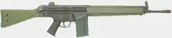 A green Heckler & Koch G3A3 battle rifle lain on a grey background, pointing to the viewer's right