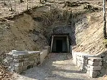 A renovated mine entrance with stone and wooden frames.