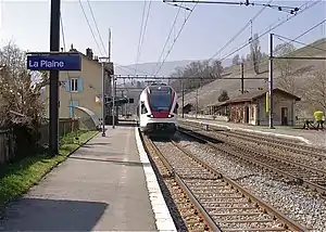 Two-story building with gabled roof and side platforms next to double-track railway line