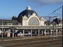 Train station with large, domed building and a high-speed train at the platform