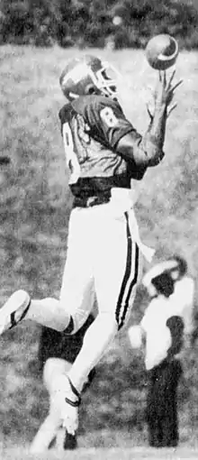 Black and white photograph of the back of Floyd in an EKU football uniform with a helmet