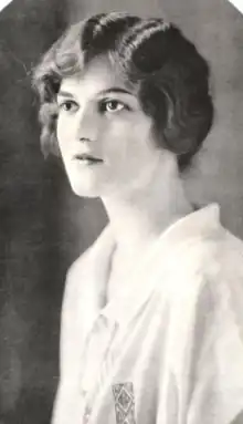 Portrait of a young white woman with dark wavy hair, wearing white collared blouse or shirt