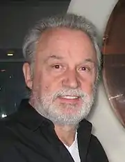 Close-up picture of a man in his late sixties. He looks at the camera and smiles