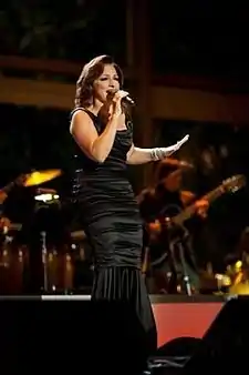 A woman wearing a black dress is performing on stage.