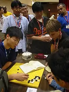 Image 6Three Japanese professional Go players observe some younger amateurs as they dissect a life and death problem in the corner of the board, at the US Go Congress in Houston, Texas, 2003. (from Go (game))