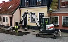 A smaller excavator is digging for the laying of a broadband cable in central Ystad in 2021.