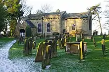 A small, one-storey church without tower, and graves in front