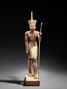 A guardian statue wearing the red crown which reflected the facial features of the reigning king, probably Amenemhat II or Senwosret II, and which functioned as a divine guardian for the imiut; made of cedar wood and plaster c. 1919–1885 BC