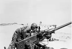 A soldier peering at the angle of his artillery gun