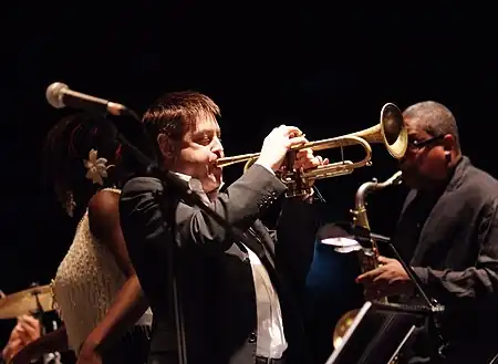 Guy Barker playing trumpet while wearing a suit