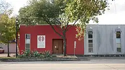 The front of a red building partially obscured by trees.