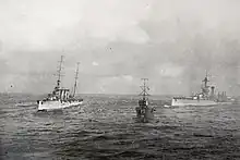 HMS Liverpool and another naval vessel, together with RMS Olympic, try to take HMS Audacious in tow. The view is from the passenger areas of RMS Olympic