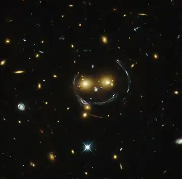 "Smiley" image of galaxy cluster (SDSS J1038+4849) & gravitational lensing (an Einstein ring) (HST).