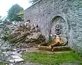 Rubble of the house ruins and remaining wall, with fountain