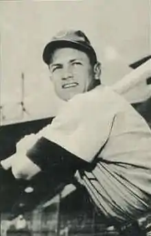 A man wearing a baseball cap and jersey poses prior–swinging his baseball bat.