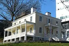 Yellow house with a staircase to the front door and veranda on the side