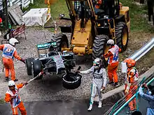 Picture of a damaged silver Formula One car being removed from the track