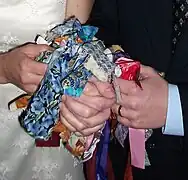 An example of a modern handfasting knot where each wedding guest has tied a ribbon around the clasped hands of the couple.