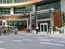 The outside of a building with a sign that reads "Hargrave St. Market". A few people are outside in the surrounding plaza.