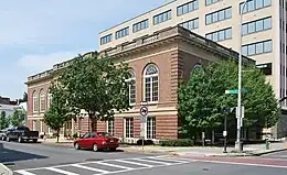 A two-story brick building with ornate windows and a flat roof seen from across a city street