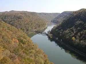 A view of a river winding through a narrow valley, flanked by forested mountain ridges.