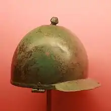  a photograph of an inverted, polished, slightly tarnished, battered bronze hemisphere