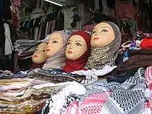 Four mannequin heads with different headscarfs are arranged on top of a display-table of colourful headscarfs.