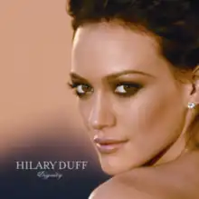 The face and shoulders of a young woman looking over her left shoulder. She has brown hair and wears small crystal earrings. To the left of her image, the words "Hilary Duff" are written in silver, capital letters, with "Dignity" in silver, italic, cursive letters below that.