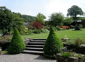 An expanse of lawn surrounded by flowers within the walled garden.