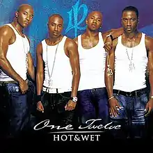 An image of four black men wearing white tank tops and blue jeans standing in front of a blue background with the group's logo.