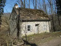 Single-storey stone building in a wooded area