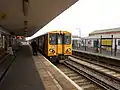 The guard waits to signal the departure of a Liverpool-bound train.