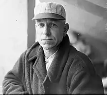 A man in a white baseball cap and heavy dark coat