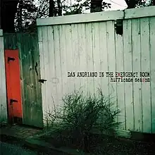 A photograph of a run-down wooden shack with a red door with "DAN ANDRIANO IN THE EMERGENCY ROOM  hurricane season" written over it black. The 'M' in "emergency" and the second 'S' in "season" are coloured red