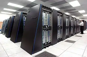 Rows of large, dark computer cabinets in huge room