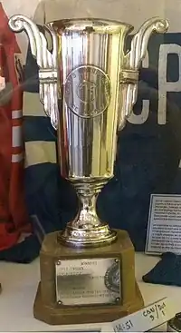 Tall slender silver cup trophy on a wooden base