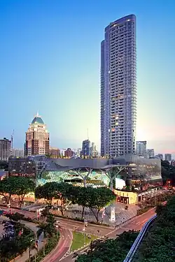 Side view of a 56-storey building attached to a luxury shopping mall in the foreground.