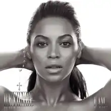 The cover of the album "I Am... Sasha Fierce" features the face of Beyoncé. She is looking directly to the camera while she keeps her hands behind her head. Her hair is combed with a ponytail, and she wears a bracelet on her right wrist. At the lower left corner her first name is written in capital silver letters, while "I Am..." is written with the same pattern at the right corner.