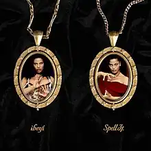 Two gold pendants lay over a sheet of wrinkled black velvet, containing photos of the two artists. The band's and album's names are written in cursive script underneath.