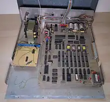 The Transam Triton with the cover removed. Image show the main circuit board with many ICs visible, a daughter board, the power supply and a UHF modulator.