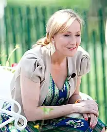 A woman with blond hair smiles while holding an honorary degree she just received