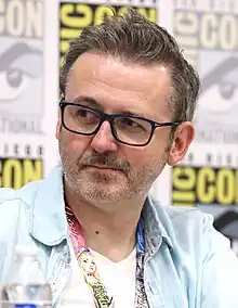 A man with brown hair in a grey and red checked shirt