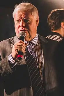 Joe Bowen looking to the right of the camera and speaking into a microphone