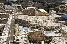 Looking down into a large excavation site, a glacis, seen in cross section, rests against a wall to the left