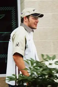 Man in his early thirties wearing a baseball cap and glasses.