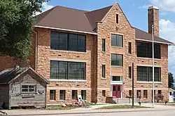 Old wooden jail (left) and stone school building in Sundance