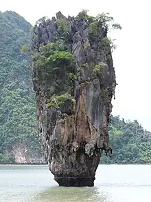  A tall rocky outcrop sitting in the sea, another island is visible, dominating the background.