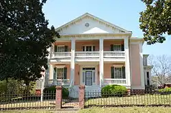 Two-story building fronted with a portico with four Greek columns