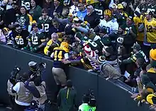 Packers runningback James Stark jumping on top of the wall around Lambeau Field, leaning in to the fans situation in the stands, after scoring a touchdown