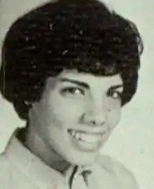 A young woman smiling, with her dark hair in a bouffant style